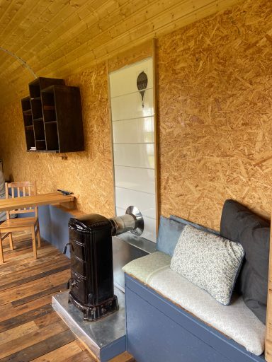 Gemütlicher Raum mit Holzvertäfelung, Sofa und einem Kachelofen.