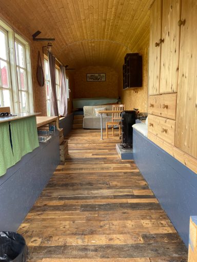 Heller Innenraum mit Holzfußboden, Fenster und Möbeln aus Holz.